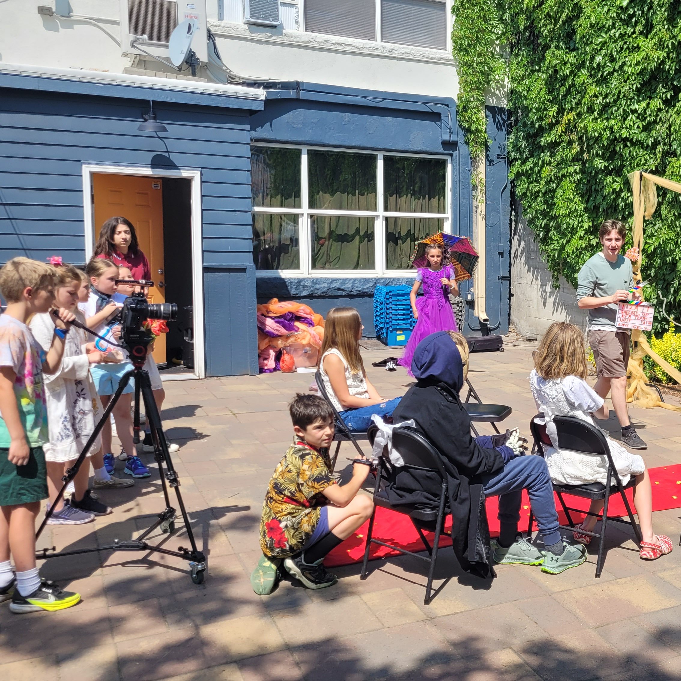Kids filming a scene outside.